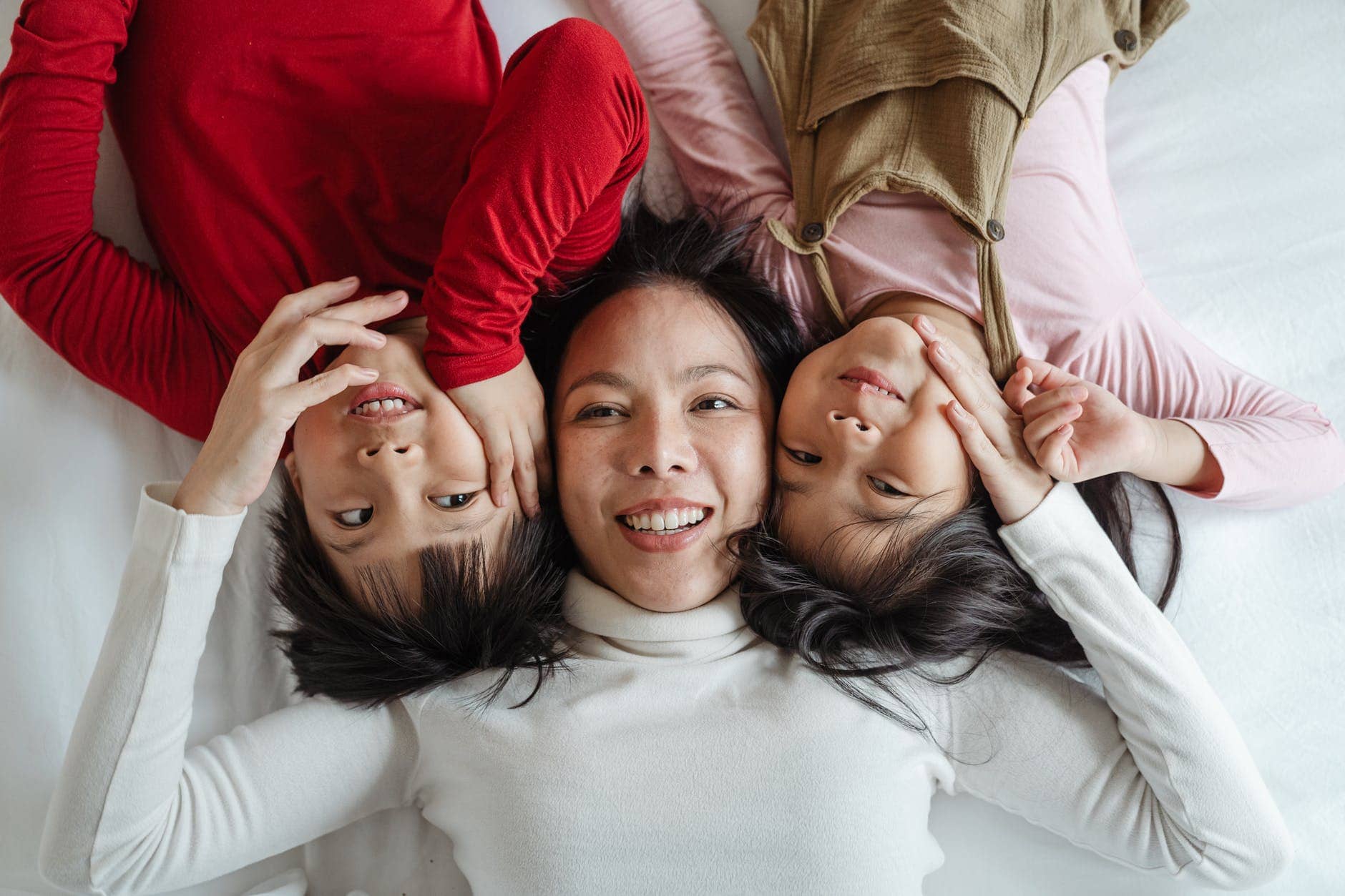 photo of woman and her children lying on bed