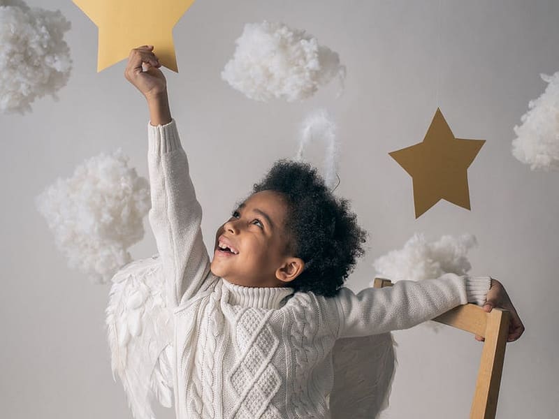 happy black boy reaching out to decorative star from chair