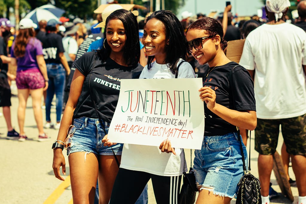 Three African-American women holding signs reading Juneteenth